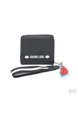 Billetera tipo monedero de color celeste claro, con cierre de cremallera y detalle frontal con texto 'MON AMOUR' en un parche blanco. Incluye un llavero desmontable con forma de labios rojos y una correa de mano negra con franjas blancas.