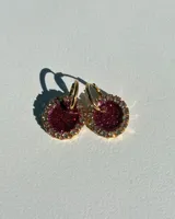 Aros colgantes dorados con dije circular de resina color borgoña con glitter y borde de strass.
