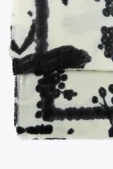 Pañuelo rectangular de color crema con estampado de ramas y flores en negro. Tiene terminaciones deshilachadas.