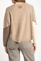 Sweater de tejido de punto con diseño de bloques de color en tonos beige, blanco roto y bordó. Presenta cuello redondo y mangas largas.