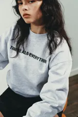 Sudadera negra de cuello redondo y manga larga, con texto blanco "SCREENWRITER & MAIN CHARACTER" en el delantero. Acabados en rib a tono.