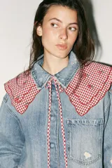 Cuello desmontable con estampado de cuadros vichy rojos y blancos, detalle de flores bordadas y volados en el borde. Se ata al frente con lazos del mismo tejido.