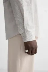 Camisa de hombre relaxed fit confeccionada en tejido de algodón a cuadros. Tiene cuello solapa, manga larga con puños abotonados, bolsillo en el pecho y cierre frontal con botones.