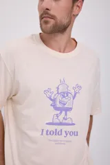 Camiseta color crema de manga corta y cuello redondo con estampado de un personaje de caricatura en color violeta y texto "I told you".