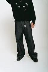 Pantalón de jean negro de corte baggy, con estampado de trigramas blancos en los bolsillos traseros.