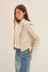 Saco corto color beige confeccionado en lino, con forro de poliéster y viscosa. Presenta solapas de muesca, cierre con un botón y corte cropped.