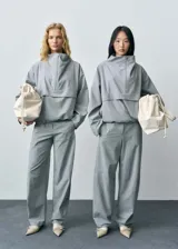 Anorak gris con cuello chimenea, diseño oversize y cierre de cremallera en el cuello.