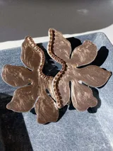 Par de aros con forma de flor roja brillante y detalle de strass plateado en el centro. Cierre a presión de acero inoxidable.