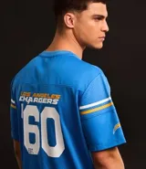 Remera deportiva azul con cuello en V y mangas cortas con rayas blancas y doradas. Estampado frontal con el logo de Los Angeles Chargers, el número 60 y la inscripción "est.". Confeccionada con tecnología Dry para mayor transpirabilidad.
