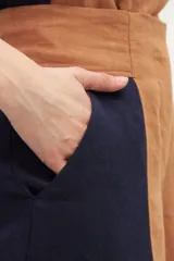 Pantalón de lino de tiro alto, con corte amplio a la cintura, confeccionado en dos colores: azul marino y marrón. Presenta un recorte delantero que estiliza la silueta. De calce cómodo.