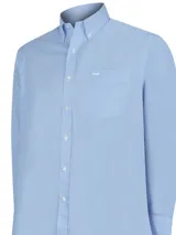 Camisa de manga larga celeste con finas rayas verticales blancas, de corte clásico y cuello abotonado. Tiene bolsillo en el pecho con logo de la marca bordado.
