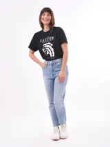 Remera negra de algodón con cuello redondo y mangas cortas. Estampado frontal con la frase "World Tour Vacation State of Mind" en letras de colores y un pequeño dibujo de una palmera.