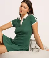 Vestido corto de mujer, estilo skater, color verde oscuro con cuello polo y ribetes blancos en el cuello, puños y hombros. Presenta un escote en V y mangas cortas.