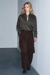 Pantalón ancho de tiro medio color marrón oscuro, confeccionado en tejido con lana. Presenta pinzas delanteras, cinturón ajustable con hebilla metálica y bolsillos cargo de plastrón en las piernas.