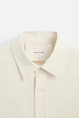 Camisa color crudo de algodón con acabado cepillado, corte relaxed fit, cuello solapa, manga larga con puño abotonado, bolsillo de parche en el pecho, efecto lavado y cierre frontal abotonado.