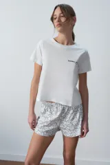 Conjunto de pijama corto blanco, compuesto por una remera de algodón con estampado de texto en el pecho y un short con estampado de corazones.