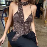 Top marrón con estampado de lunares blancos, escote halter y tiras finas. Incluye una tira de tela que se ata al cuello.