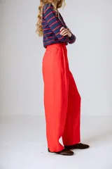 Pantalón negro de corte ancho y tiro alto, con pinzas en la cintura y bolsillos laterales.