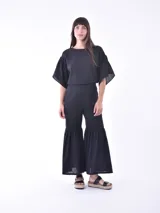 Blusa negra de mangas cortas con volados y escote redondo.
