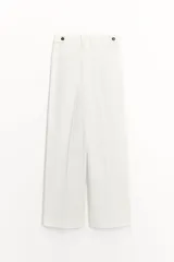 Pantalón blanco de tiro medio con pinzas delanteras y raya planchada. Confeccionado en hilatura con mezcla de algodón. Presenta bolsillos laterales, trabillas en la cintura y cierre frontal con cremallera, botón y gancho metálico.