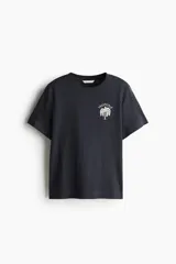 Remera negra de corte holgado en punto de algodón con cuello redondo y estampado de palmera con texto en el frente.