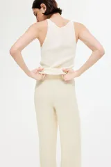 Pantalón de corte holgado color crema, confeccionado en tejido de punto con textura. Modelo de tiro alto con cintura elástica y piernas rectas.