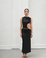 Vestido largo negro de lycra, sin mangas y con abertura lateral en la pierna. Presenta un corte en la cintura con detalle de cadena dorada.
