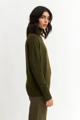 Sweater color crema de tejido de punto, con cuello alto y mangas largas.