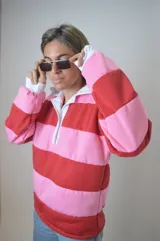 Sweater a rayas rojas y rosas, con cuello tipo polo y mangas largas.