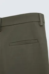 Pantalón verde oliva de corte amplio con pliegues en la parte delantera, bolsillos laterales y traseros de ojal.