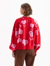 Buzo rojo de calce amplio, confeccionado en tela de punto con estampado de cerezas en color rosado. Presenta cuello redondo, puños y bajo en tejido liso a tono.