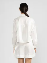 Camisa azul marino de lino italiano con hilo metalizado, cuello clásico, silueta fluida y botón en forma de flor en el cuello.