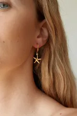 Aros tipo argolla de acero quirúrgico hipoalergénico, color dorado, con un dije colgante de estrella de mar texturizada.