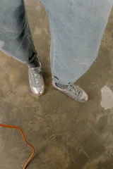 Zapatilla plateada de cuero con detalles de gamuza gris y costuras visibles.