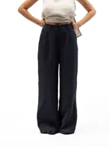 Pantalón largo de vestir color azul marino, corte ancho y tiro alto con pliegues frontales. Presenta bolsillos laterales inclinados y bolsillos traseros ribeteados. La cintura es ajustable con elástico en la parte trasera.