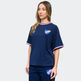 Remera blanca de mujer con cuello y mangas con detalles tricolor (azul, blanco y rojo), logo de Umbro bordado en negro y escudo del Club Nacional de Football estampado.
