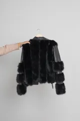 Cazadora negra de cuerina con detalles de piel sintética en cuello y puños, cierre metálico plateado y forro interior.