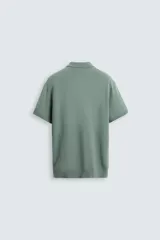 Polo verde salvia de punto canalé, corte regular fit, cuello solapa con cierre de botonadura y mangas cortas.