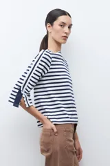 Buzo de cuello redondo con estampado de rayas horizontales blancas y azul marino. Presenta mangas de largo 3/4 con un panel lateral en contraste, botones decorativos y terminación en volados.