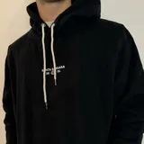 Canguro blanco con capucha y cordones ajustables, puños y cintura acanalados. Estampado en la espalda con un sol, olas y la frase "Chasing the waves Santa Barbara".