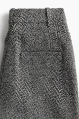 Pantalón de vestir gris con estampado de espiga, de corte holgado y tiro alto, con elástico oculto en la cintura, cierre, bolsillos al bies y bolsillos decorativos insertados atrás.