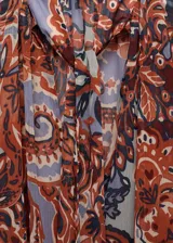 Vestido corto evasé con estampado paisley en tonos marrón, naranja y lila. Tiene cuello redondo con lazo, mangas largas con volantes, forro interior y cinturón desmontable.