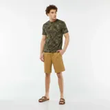 Camiseta de manga corta color verde militar con estampado de hojas de palma en tonos verde claro y negro.