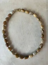 Collar de cuentas de piedra natural en tonos marrones y beige, con cierre de mosquetón dorado.