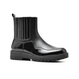 Bota Chelsea de cuero sintético charolado color negro, con elásticos laterales y tirador trasero. Tiene suela track y plataforma.