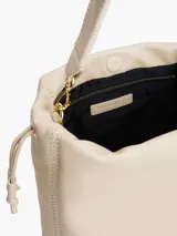 Cartera bombonera color crema con correa de hombro y cierre con cordón ajustable.