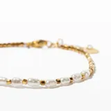 Pulsera dorada con cadena de eslabones pequeños y detalle de perlas irregulares.