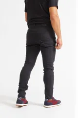Jean skinny de hombre color negro, ajustado desde la cadera hasta los tobillos, con roturas en las rodillas y logo bordado en el bolsillo trasero.