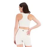 Conjunto deportivo New Balance color crema, compuesto por un top con logo en el pecho y un short ajustado con logo en la pierna.