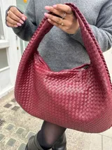 Cartera de hombro color bordó con diseño tejido.